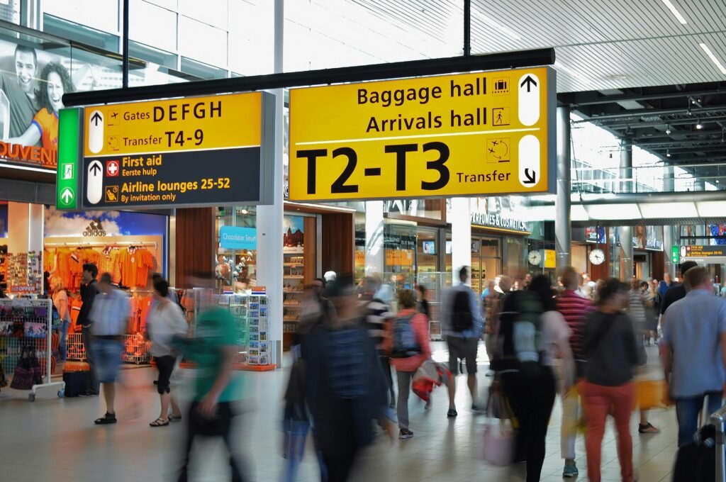 Crowded airport with motion blur and clear signage indicating baggage and arrival halls.