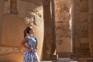 Woman in Luxor Temple admiring ancient carved columns in sunlight.