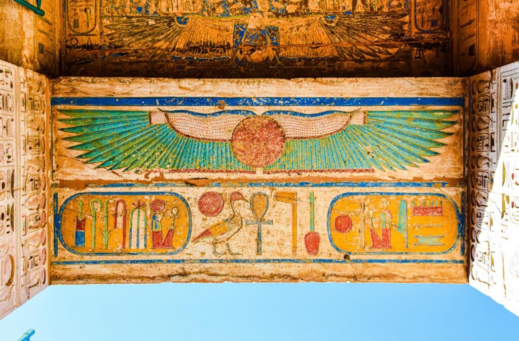 Vibrantly painted ancient Egyptian lintel with symbolic art in Luxor, showcasing rich historical craftsmanship.