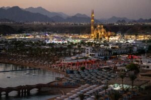 A stunning evening view of the illuminated resort area of Sharm El-Sheikh, Egypt, featuring a lit mosque and surrounding mountains.