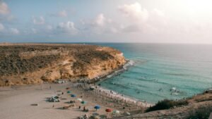 Panoramic summer view of Marsa Matruh beach with cliffs and turquoise water.