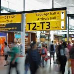 Crowded airport with motion blur and clear signage indicating baggage and arrival halls.