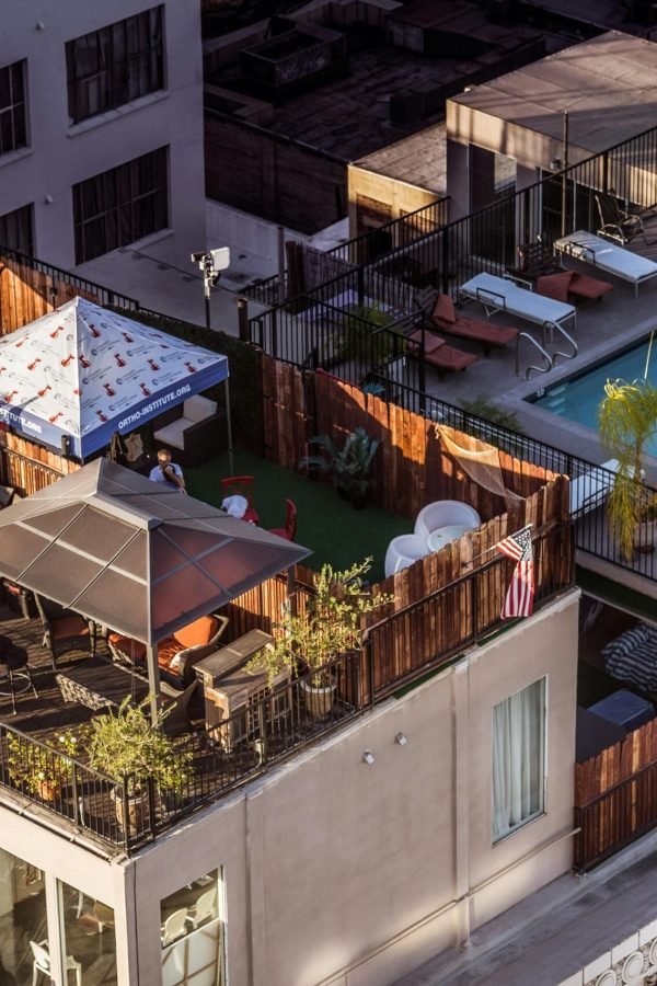 An aerial view of a stylish rooftop terrace with a pool and seating area in a city setting.